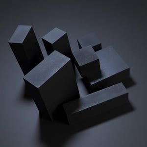 May include: An abstract composition of several black rectangular blocks of varying sizes. The blocks are arranged in a seemingly random configuration, casting shadows on a dark gray surface. The overall aesthetic is minimalist and modern.