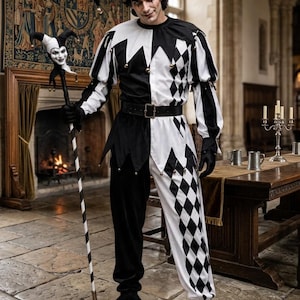 Könnte beinhalten: Ein schwarz-weißes Narrenkostüm bestehend aus einer zweifarbigen Tunika mit Rautenmuster auf einer Seite, einer passenden Narrenkappe mit Glöckchen und einem schwarzen Gürtel. Das Outfit umfasst einen Stab mit einem kleinen Narrenkopf und spitze Schuhe.