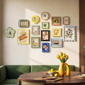 Op de afbeelding: Een galerijmuur met vijftien diverse decoratieve lijsten in verschillende vormen en kleuren, waaronder geschulpte, rechthoekige en bloemvormige ontwerpen. De lijsten bevatten illustraties van voedsel, planten en de tekst Les Baguettes.