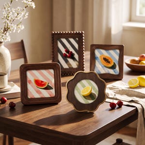 May include: Four wooden picture frames of varying shapes and sizes, each containing a print of a fruit slice against a striped background. The frames include a square, a rectangle with beaded edges, a square with rounded corners, and a flower-shaped frame.