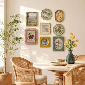 May include: A gallery wall arrangement featuring eight diverse wall frames with various shapes and textures, including beaded, scalloped, and smooth edges, displaying botanical, landscape, and still life art prints, positioned above a round dining table.