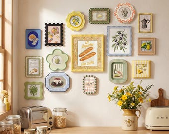 May include: A gallery wall arrangement featuring fifteen assorted decorative frames in various shapes, colors, and sizes. The frames display illustrations of food, plants, and kitchen items, including a central print with the text Les Baguettes bien cuites.