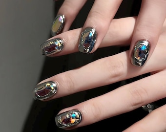 Unghie finte Liquid Chrome, argento metallizzato effetto specchio, unghie ovali corte in vetro dal design futuristico.