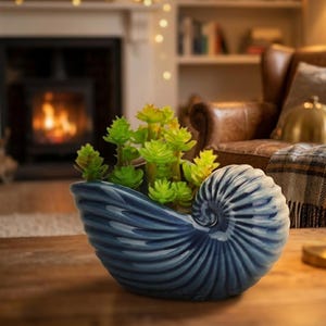 May include: A trio of cream-glazed ceramic mugs with a speckled finish. Each mug is adorned with a hand-painted design: a blue and green leaf, a yellow flower, and a red berry. The mugs have a simple, rounded form.