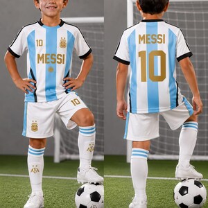 May include: A soccer uniform featuring a white and light blue striped jersey with the name MESSI and number 10 in gold, matching white shorts with the number 10, and white knee-high socks with blue stripes and the AFA logo, paired with white cleats.