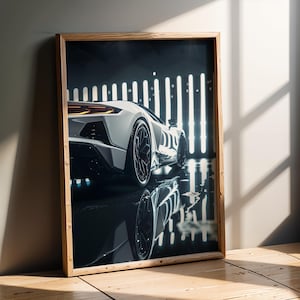 May include: Framed print of a white sports car, angled to show the rear and side. The car is in a dark garage with vertical lights, reflected in the wet floor. The frame is made of light-colored wood.