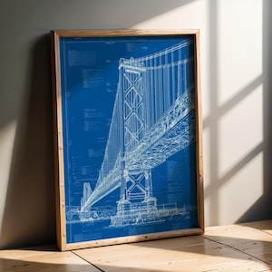Könnte beinhalten: Ein gerahmter Wandkunstdruck mit einer detaillierten weißen Strichzeichnung einer Hängebrücke auf blauem Hintergrund. Das Kunstwerk ähnelt einem technischen Bauplan und enthält feine Textanmerkungen sowie strukturelle Diagramme.