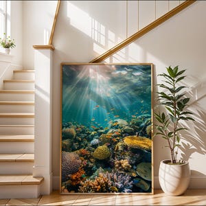 May include: A rectangular framed wall art print featuring an underwater scene of a vibrant coral reef. The image displays various textures of coral in shades of yellow, orange, and purple, with small orange fish swimming through sunlit water.