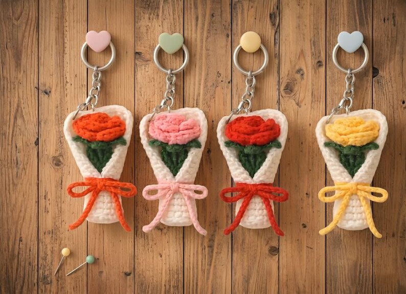 May include: Four handmade crochet flower bouquet keychains. Each keychain features a different colored flower: orange, pink, red, and yellow. The bouquets are wrapped in white yarn and tied with a matching bow. Each keychain has a heart-shaped charm.