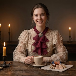 May include: A woman smiles, seated at a wooden table, surrounded by lit candles in ornate holders. She wears a cream-coloured lace blouse with a burgundy ruffled collar and holds a cup. A small doily and bobbins are on the table.