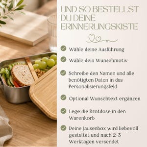 Peut inclure: Une bo&icirc;te &agrave; lunch en acier inoxydable avec un couvercle en bois, contenant un sandwich, des raisins et des noix. L'image montre &eacute;galement un verre d'eau et du texte en allemand.