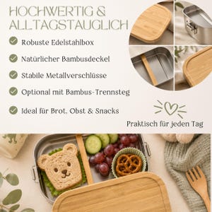 Peut inclure: Une bo&icirc;te &agrave; lunch en acier inoxydable avec un couvercle en bambou, contenant un sandwich en forme d'ours, des raisins, des tranches de concombre et un bretzel. Le texte de l'image indique "HOCHWERTIG & ALLTAGSTAUGLICH" et "Praktisch f&uuml;r jeden Tag."