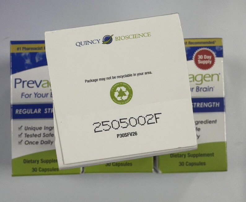 Peut inclure: Bo&icirc;te blanche de compl&eacute;ments alimentaires avec le logo Quincy Bioscience. La bo&icirc;te porte la mention "Package may not be recyclable in your area" et le num&eacute;ro "2505002F". D'autres bo&icirc;tes sont visibles en arri&egrave;re-plan.