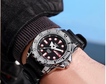 May include: A stainless steel Seiko automatic watch with a black dial, red accents, and a black leather strap. The watch features a rotating bezel and is displayed on a wrist.