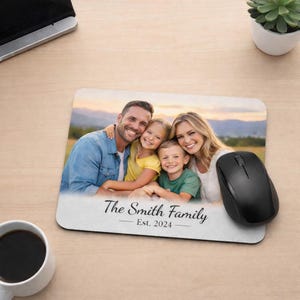 May include: A rectangular mousepad with a family photo and the text "The Smith Family Est. 2024". A black computer mouse sits to the right. A cup of coffee is on the left.