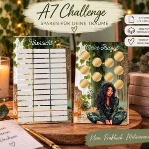 Könnte beinhalten: Zwei A7-Spar-Challenge-Karten im Format 74 x 105 mm. Eine Karte zeigt ein weißes Raster mit der Überschrift "Übersicht", die andere goldene Rubbelkreise und eine Illustration einer Person mit langem dunklen Haar mit der Aufschrift "Meine Auszeit".