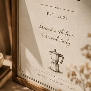 以下が含まれることがあります： 上部に「CAFE」の文字が入った額入りの看板。看板には「EST. 2024」と「brewed with love & served daily」と書かれています。テキストの下にはコーヒーポットのスケッチがあります。看板の下部には「FLAT WHITE . CORTADO . LATTE」と記載されています。