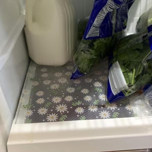 May include: A white ceramic mug with a black handle and the text "But First, Coffee" in a bold, black font. The mug is set against a blurred background, suggesting a cozy setting.