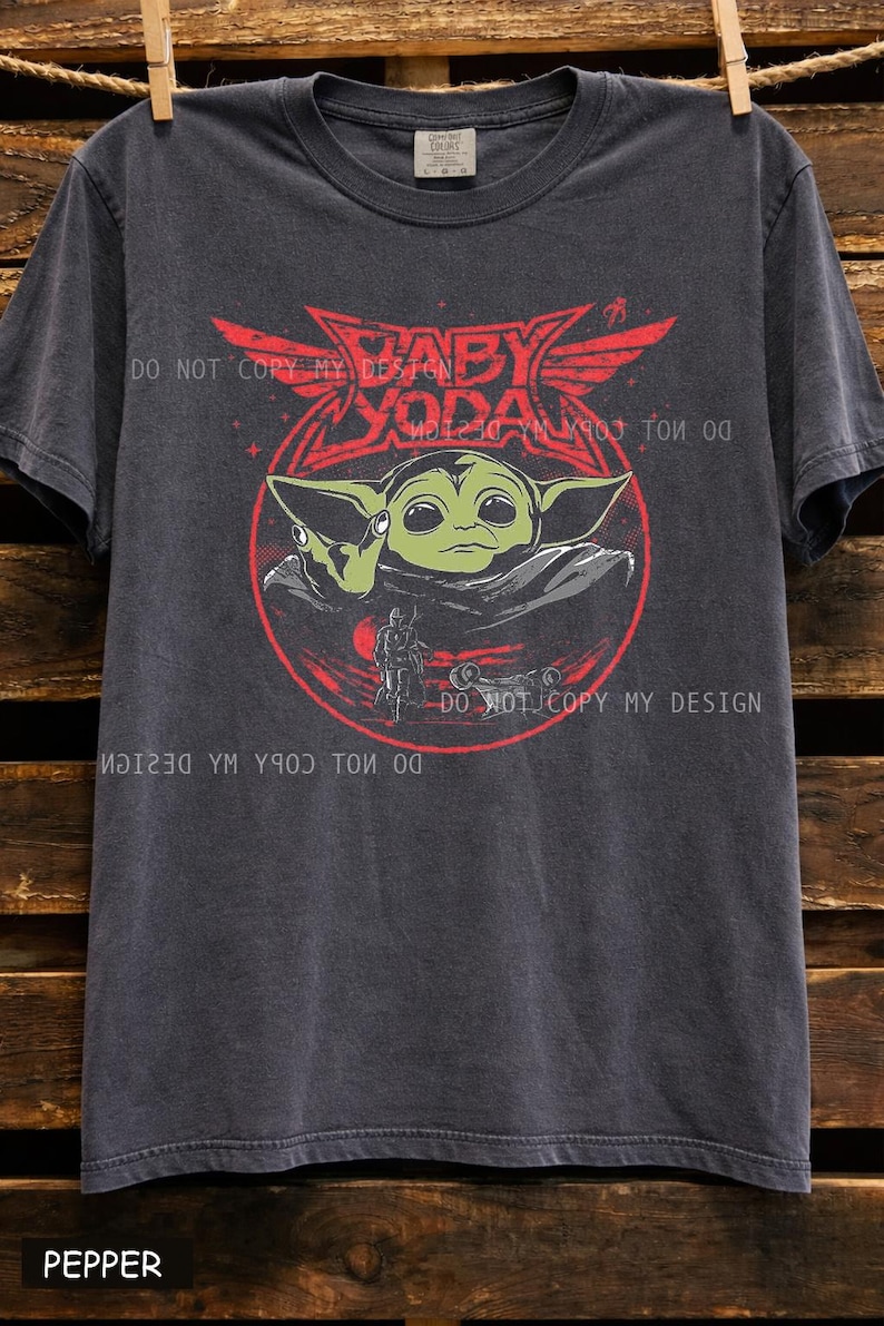 Oversized faded black graphic t shirt featuring a retro inspired baby alien character design with red and green vintage sci fi artwork, unisex casual streetwear tee for space fantasy fans.