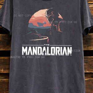 Oversized vintage black graphic t shirt featuring The Mandalorian and Grogu inspired sci fi sunset design, unisex Star Wars fan apparel with retro aesthetic print.