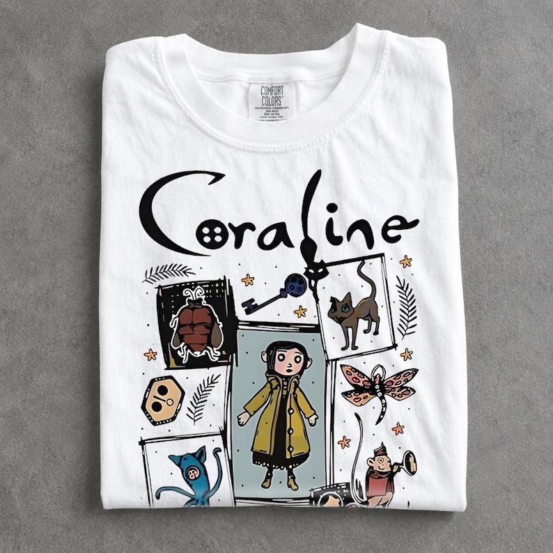 May include: A white short-sleeved t-shirt featuring the text Coraline in black lettering. The graphic includes a central illustration of a character in a yellow raincoat surrounded by various icons including a key, a cat, a dragonfly, and other figures.