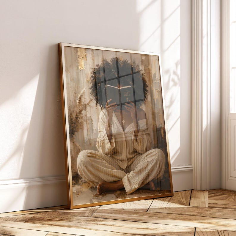 Pu&ograve; includere: Una stampa artistica incorniciata raffigurante una persona con capelli scuri e ricci seduta a gambe incrociate mentre tiene un libro aperto davanti al viso. La persona indossa una camicia beige chiaro abbottonata e pantaloni abbinati in stile pittorico.