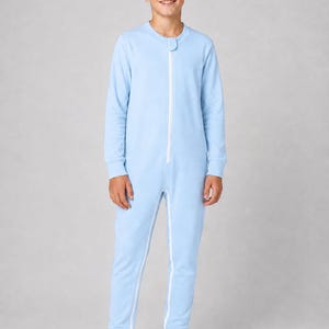 Può includere: Una tuta intera color azzurro a maniche lunghe, con scollo rotondo e una chiusura a zip bianca che corre lungo tutta la parte anteriore. Il capo presenta polsini a coste sia sui polsi che sulle caviglie per una vestibilità aderente.