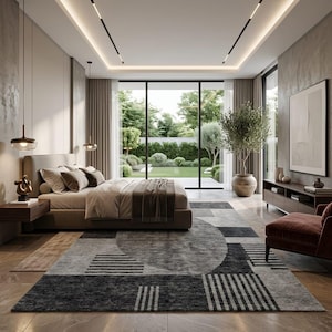 Peut inclure: Une chambre moderne avec une grande fenêtre donnant sur un jardin verdoyant. La pièce comprend un lit avec une literie aux tons neutres, un tapis à motifs gris et noir, et un fauteuil marron. Un grand olivier en pot ajoute une touche naturelle.