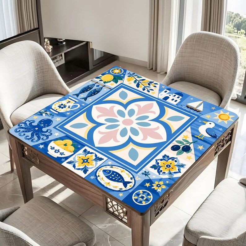 May include: A square wooden table with a blue, white, and yellow patterned top. The design features floral and nautical motifs, including fish, an octopus, and a sailboat. The table is surrounded by light-colored chairs.