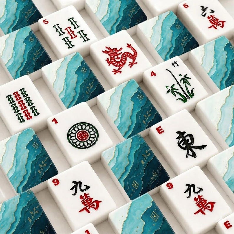 May include: A collection of white mahjong tiles featuring a mix of traditional black and red character symbols, numbers, and bamboo designs, interspersed with tiles displaying a decorative teal and blue wavy pattern with gold accents.