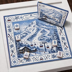 Peut inclure: Un tapis de jeu carré et une pochette zippée assortie présentant une scène de montagne hivernale bleue et blanche avec des pistes de ski, des téléphériques et un chalet. Le tapis inclut le texte Personalized et cinq tuiles blanches.