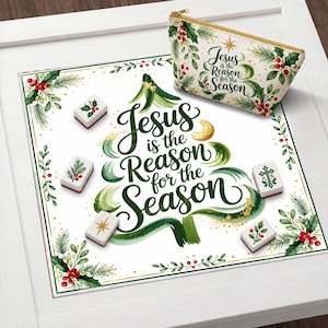 May include: A white square mat and a matching zippered pouch featuring green watercolor pine branches, red holly berries, and the text "Jesus is the Reason for the Season" in green script. Five white rectangular tiles with holiday icons are included.