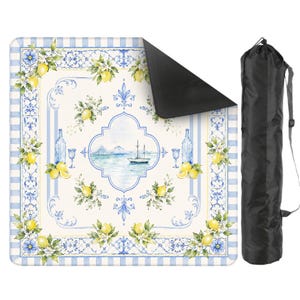 Peut inclure: Une couverture de pique-nique avec une bordure &agrave; carreaux bleus et blancs et un motif central repr&eacute;sentant des citrons, des fleurs et une sc&egrave;ne c&ocirc;ti&egrave;re. La couverture est enroul&eacute;e et rang&eacute;e dans un sac de transport noir avec une bandouli&egrave;re.