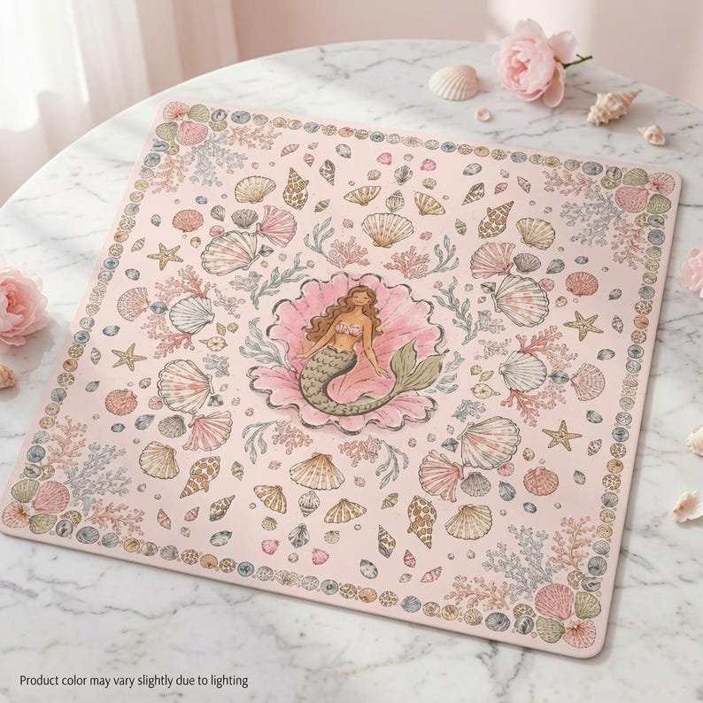 May include: A square light pink mat featuring a central illustration of a mermaid resting inside a large open seashell. The surrounding area is decorated with a repeating pattern of various seashells, starfish, and coral in soft pastel tones.