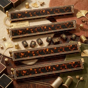 Puede incluir: Cuatro soportes rectangulares para mahjong con un patr&oacute;n de carey en tonos marr&oacute;n oscuro y naranja, con bordes de metal dorado. Una etiqueta peque&ntilde;a dice Aged Resins Hand finished Luxury Tortoise-shell. Incluye varias fichas de mahjong con caracteres dorados.