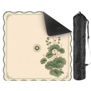 May include: A square mat with a cream-colored surface, a scalloped green border, and a botanical illustration of pink lotus flowers and green leaves. The mat has a black underside and is accompanied by a black cylindrical carrying bag with a strap.