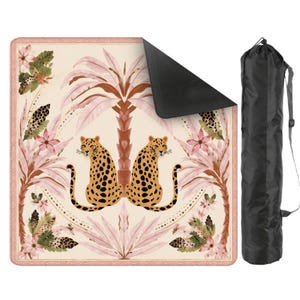 May include: A beige yoga mat with a leopard and palm tree design. The mat features two leopards with black spots, pink palm trees, and floral accents. A black carrying bag is included. The mat has a decorative border.