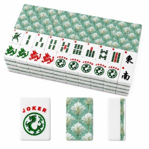 May include: A complete Mahjong set with white tiles featuring red and green symbols and characters. The tiles are stacked, with a decorative floral pattern on the back. One tile reads "JOKER" with a green dragon.