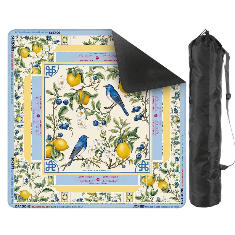 Puede incluir: Una alfombrilla cuadrada con un dise&ntilde;o bot&aacute;nico con limones, ar&aacute;ndanos y p&aacute;jaros azules. La alfombrilla tiene un borde azul claro con texto y va acompa&ntilde;ada de una bolsa de transporte negra. La alfombrilla est&aacute; dise&ntilde;ada para un juego de cartas.