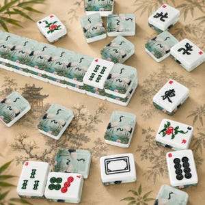 Może przedstawiać: Zbi&oacute;r białych i zielonych płytek do gry w Mahjong z r&oacute;żnymi symbolami i ilustracjami. Niekt&oacute;re płytki przedstawiają żurawie w spokojnym krajobrazie, inne chińskie znaki i wartości liczbowe. Płytki ułożone są na powierzchni z kwiatowym wzorem.