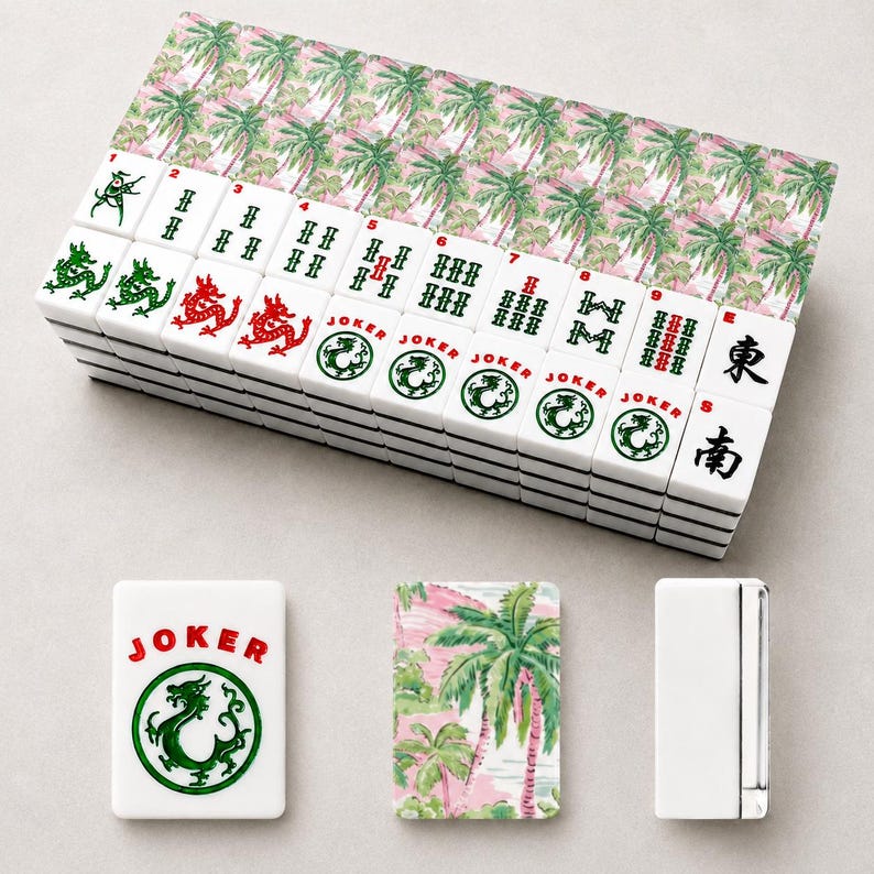 May include: A complete Mahjong set with white tiles featuring green and red dragon designs, numbers, and Chinese characters. The set includes a box with a pink and green palm tree pattern. Additional tiles and a lighter are also visible.