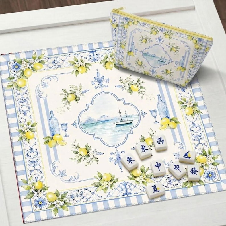 Peut inclure: Un ensemble d&eacute;coratif sur le th&egrave;me des citrons. Il comprend un tapis rectangulaire avec une bordure &agrave; rayures bleues et blanches, une pochette zipp&eacute;e assortie et des tuiles de Mahjong. Le tapis et la pochette pr&eacute;sentent une illustration &agrave; l'aquarelle d'un paysage marin.