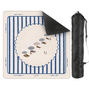 May include: A beach mat with a whimsical illustration of a beach scene, featuring blue and white striped borders and a central design of beach umbrellas and sunbathers. Includes a black carrying bag with a shoulder strap.