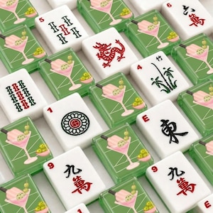 May include: A collection of white Mahjong tiles with various symbols and numbers. Some tiles feature a red dragon, bamboo, or a flower design. Other tiles have a cocktail design with green olives.