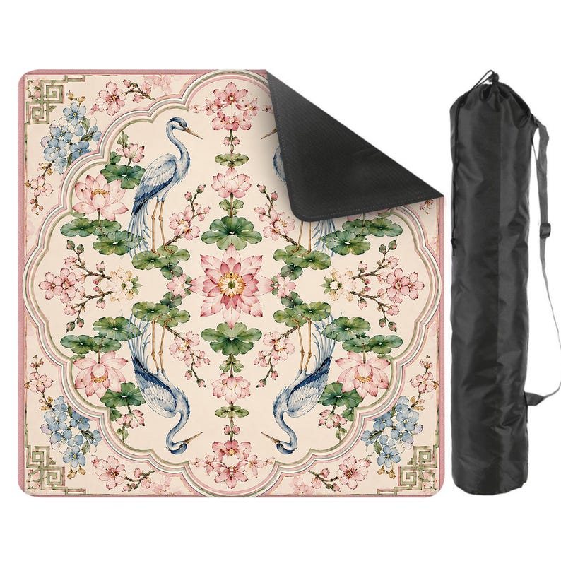 May include: A yoga mat with a floral design featuring pink and blue flowers, green leaves, and blue herons. The mat has a pink border and a black underside. A black carrying bag is included.