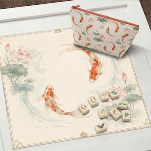 May include: A cream-colored mat with a koi fish and lotus flower design, with a matching cosmetic bag. Several Mahjong tiles are scattered on the mat. The koi fish are orange and white, and the bag has a zipper closure.