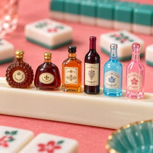 Könnte beinhalten: Ein Set aus sechs dekorativen Miniaturflaschen in verschiedenen Formen und Farben, darunter bernsteinfarbenes, dunkelrotes und klares Glas mit blauen und rosa Tönen. Jede Flasche hat ein einzigartiges Etikett mit grafischen Motiven wie Trauben und Blumen.