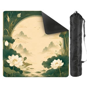 May include: A square mat featuring a cream-colored circular center with a landscape of mountains and birds, surrounded by dark green lotus flowers and leaves. The mat has a black underside and comes with a black cylindrical carrying bag with a strap.