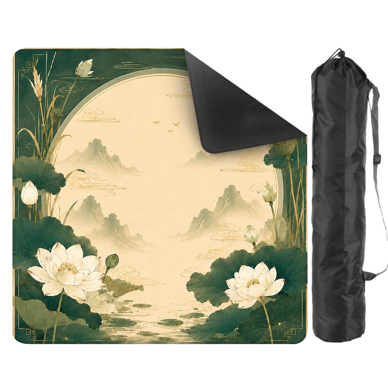 May include: A square mat featuring a cream-colored circular center with a landscape of mountains and birds, surrounded by dark green lotus flowers and leaves. The mat has a black underside and comes with a black cylindrical carrying bag with a strap.