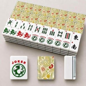 May include: A set of white Mahjong tiles featuring green and red ink designs, including dragons, numbers, and Joker labels. The back of each tile displays a detailed floral pattern in shades of yellow, green, and red on a light cream background.
